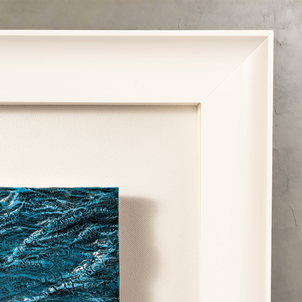 Close view of a white shadow-box frame and blue three-dimensional textured artwork