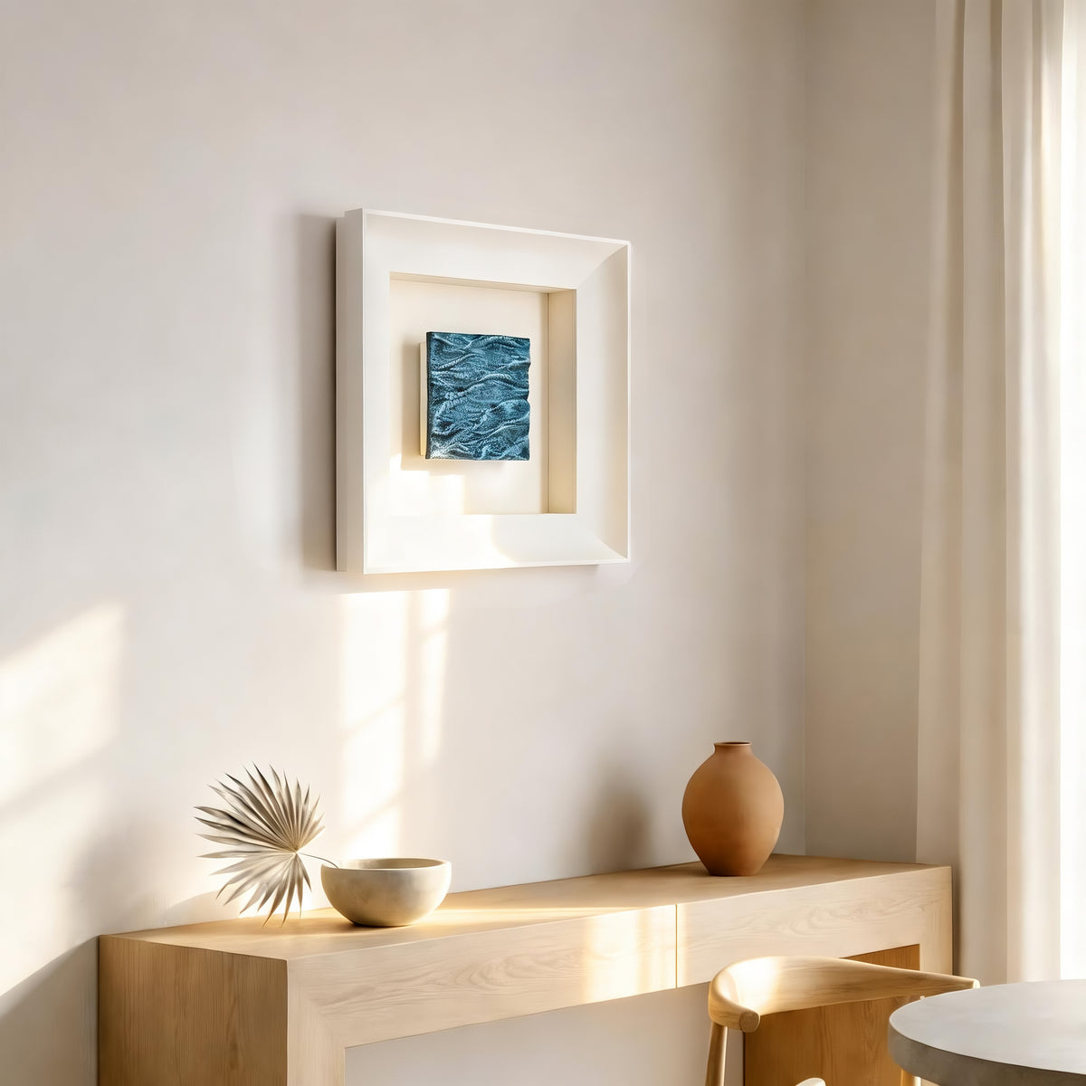 Small framed blue wall art above a wood console in a softly lit neutral interior